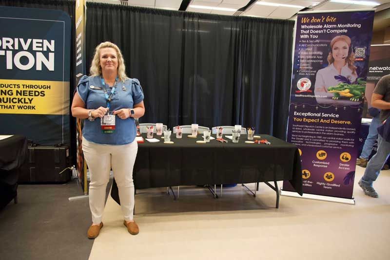 Woman at a trade show booth with products and promotional banners.