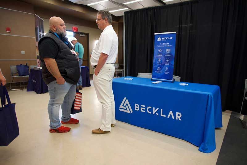 Two men talking at a trade show booth.