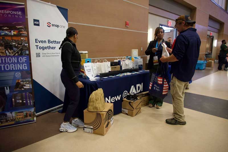 People at a trade show booth with a blue table and banner. 