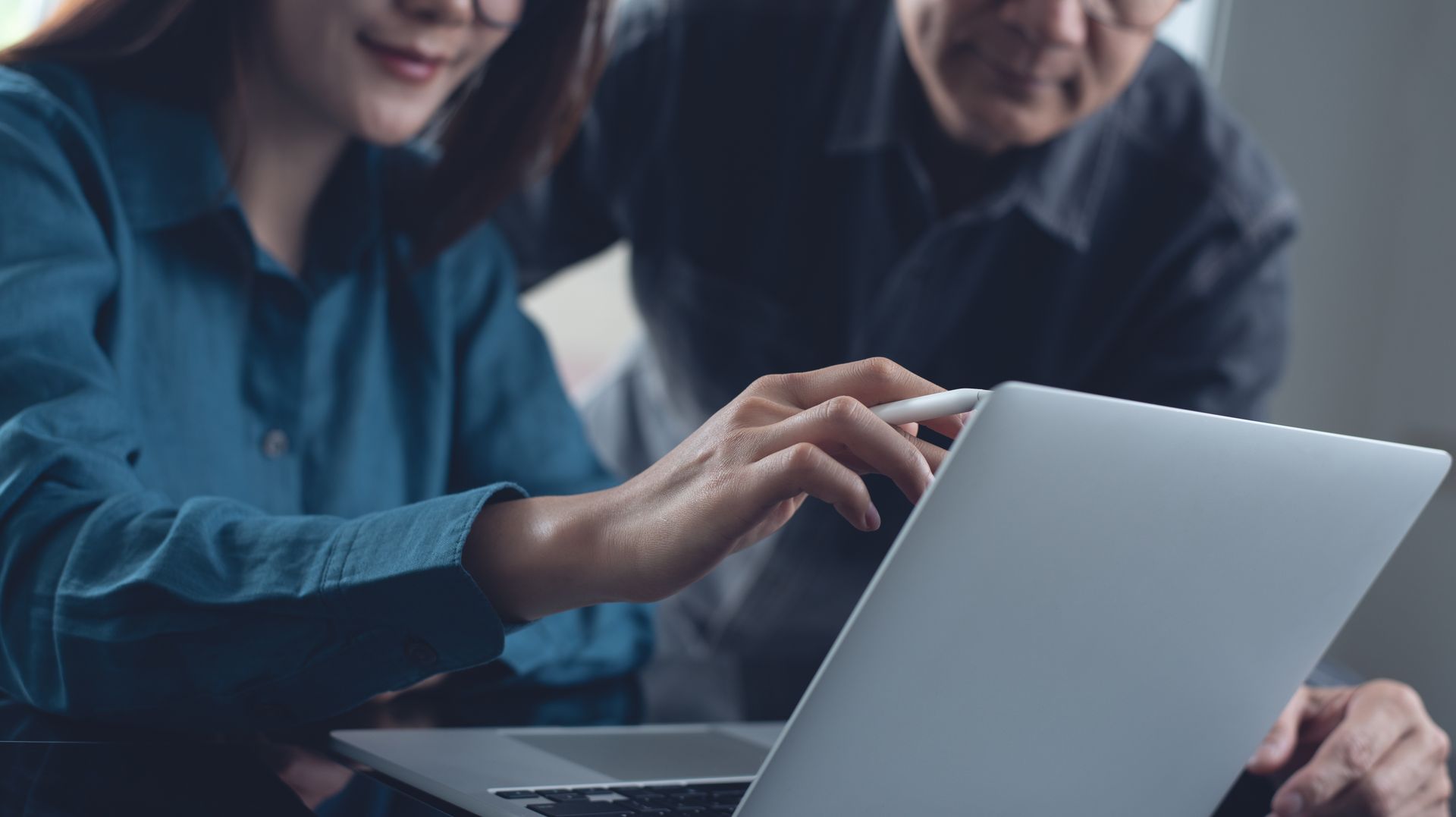 Woman pointing at laptop screen with a man, indoors.