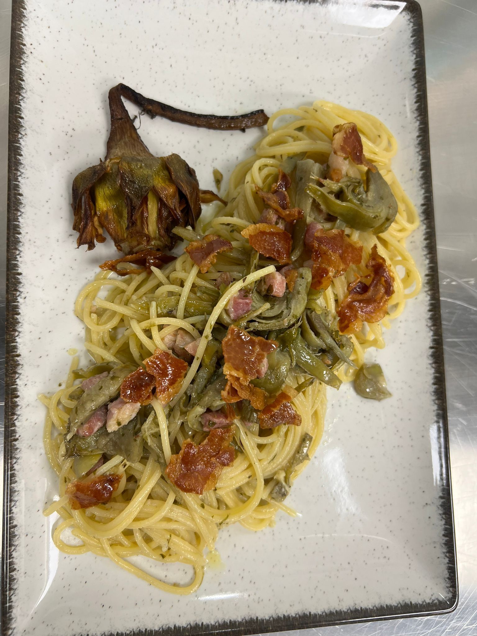 Piatto di spaghetti con verdure grigliate e salsa di pomodoro su un piatto bianco.