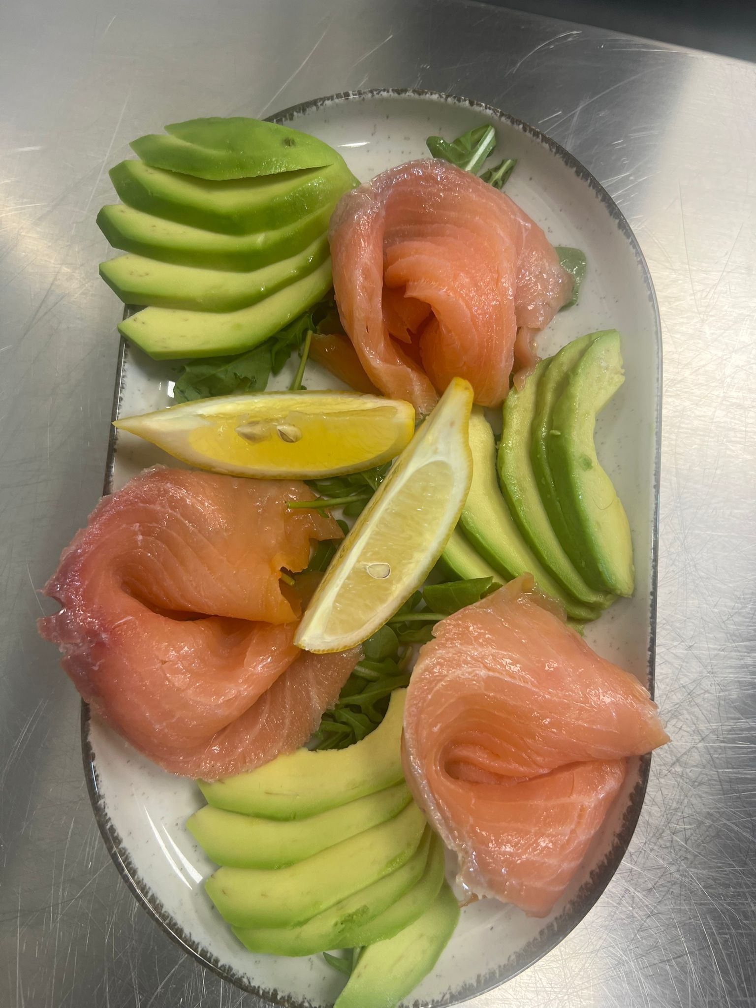 Sashimi di avocado e salmone con spicchi di lime su un piatto bianco