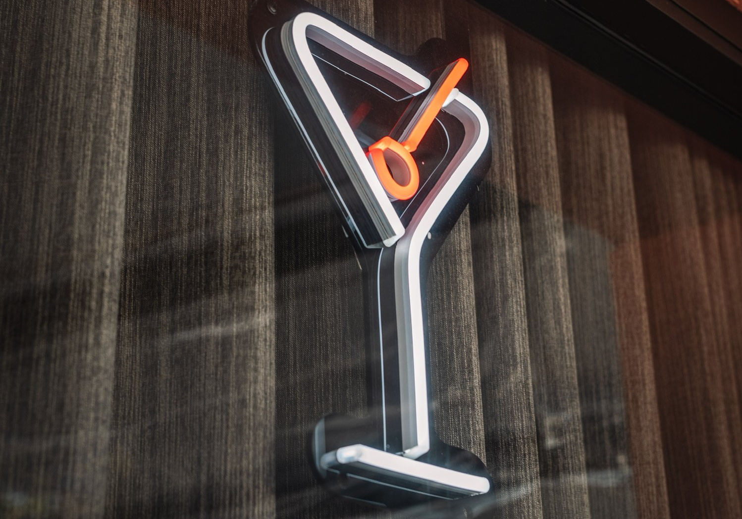 Neon martini glass sign on a wooden wall.