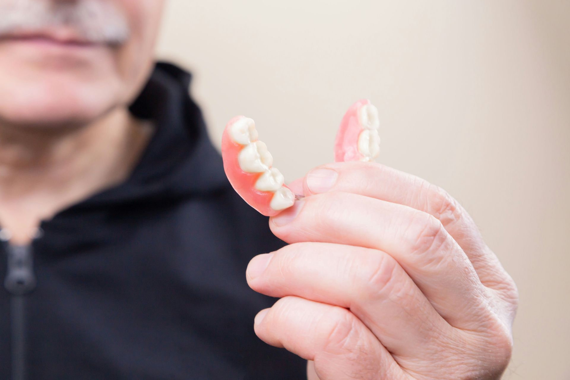 Person holding a clear dental retainer near their face.
