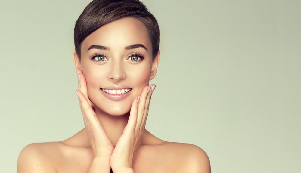 Smiling woman with hands on cheeks against a soft green background