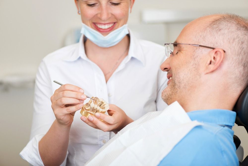Dentist showing dental mold to smiling patient in a clinic