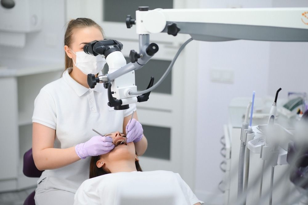 Dentist examining a patient with a dental microscope in a bright clinic