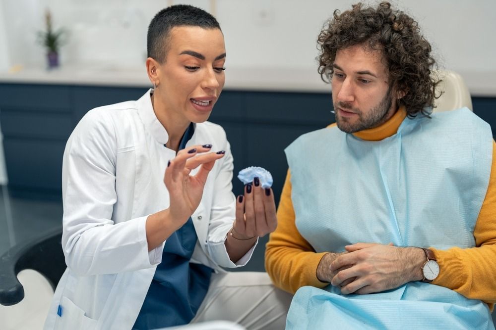 Dental professional showing a patient a tooth model during a consultation in a clinic