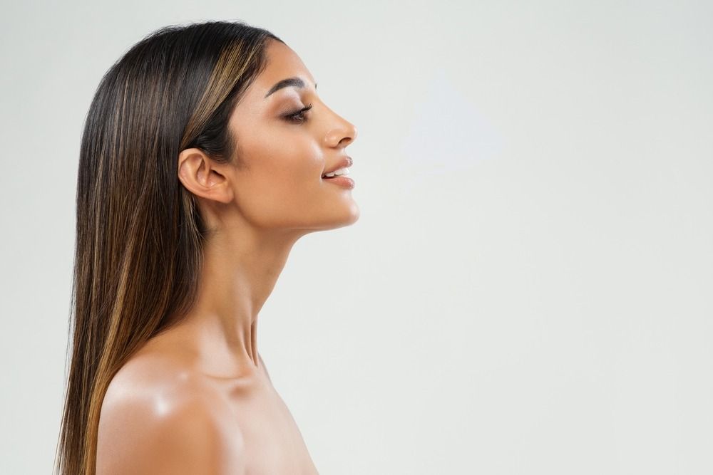 Profile of a woman with long dark hair, facing left against a light gray background
