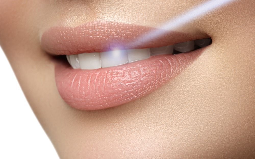 Close-up of glossy pink lips with a small white tooth visible and a subtle shine.
