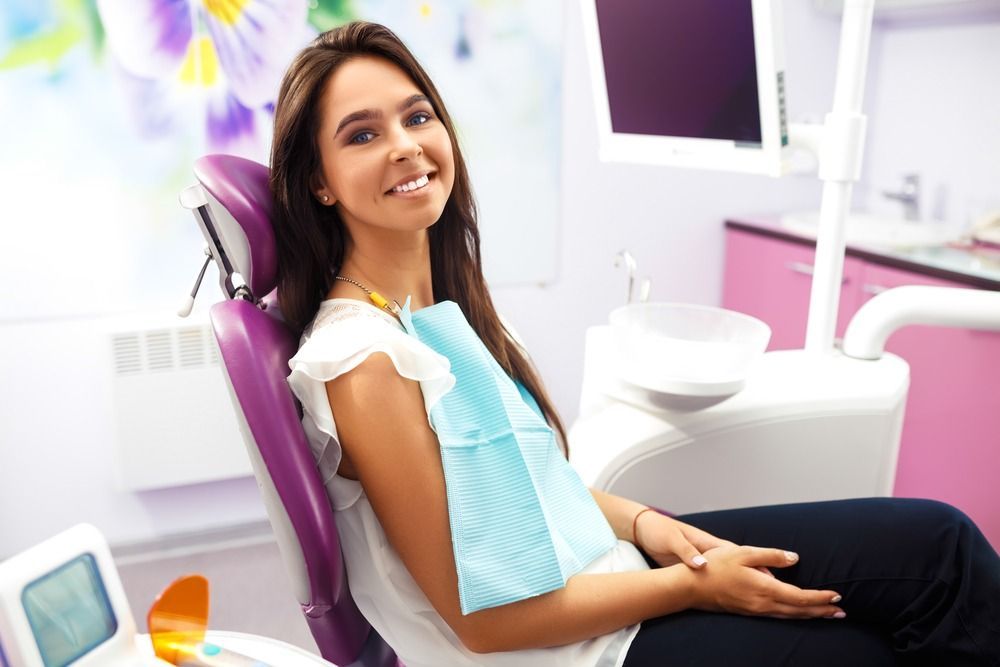 Smiling patient seated in a dental chair in a bright pink-and-white clinic