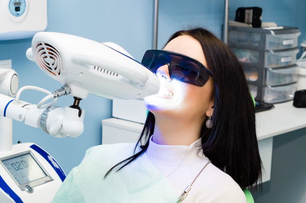 Woman receiving a bright cosmetic treatment from a handheld device in a clinic