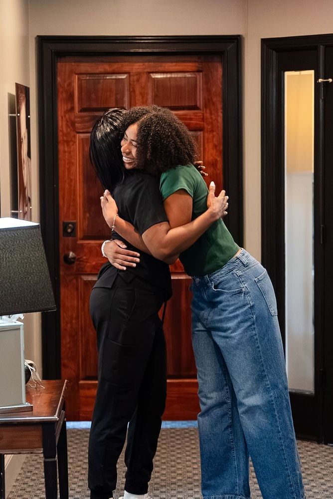Two people hugging indoors in front of a wooden door
