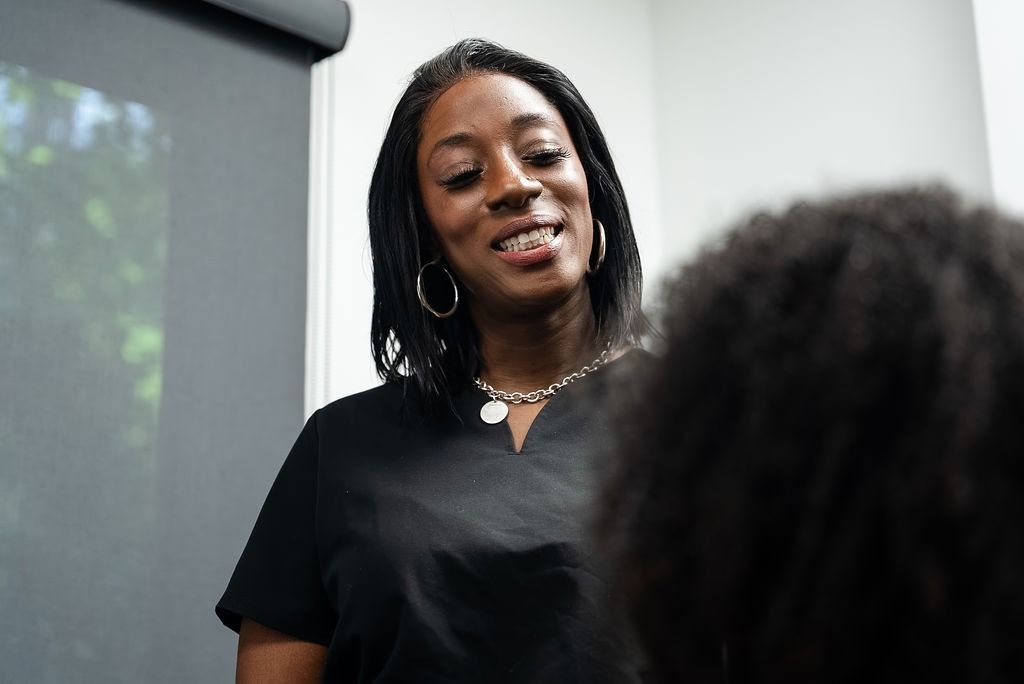Woman speaking in a black shirt, smiling during a conversation indoors