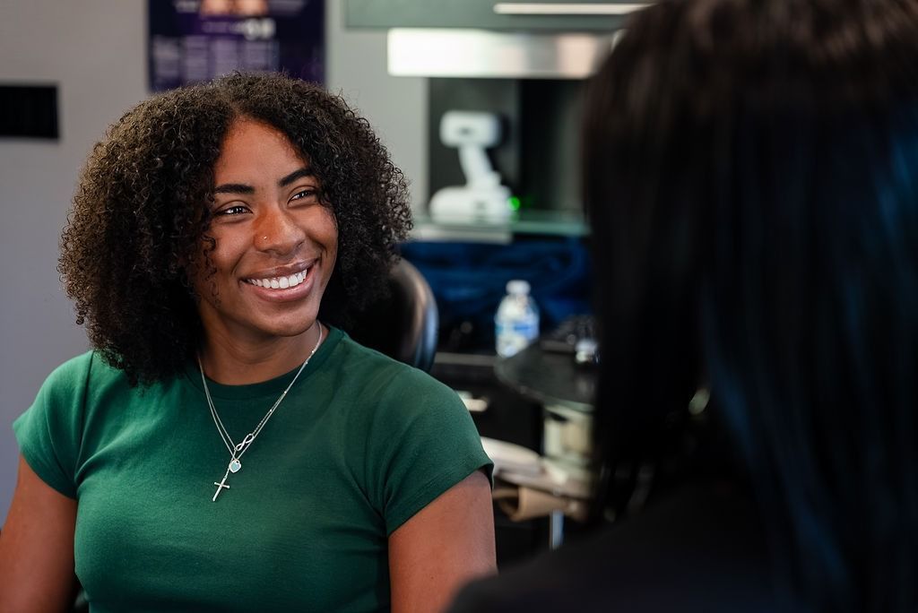 Smiling woman in a green shirt talking in an office setting.