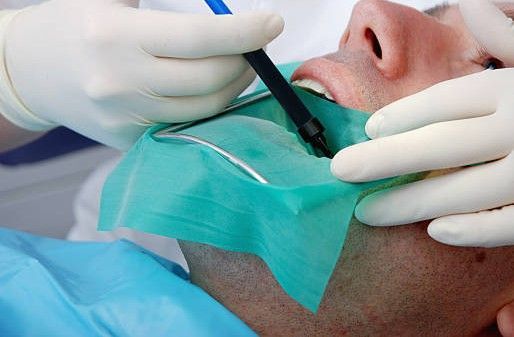 Gloved hands performing a dental procedure on a patient.