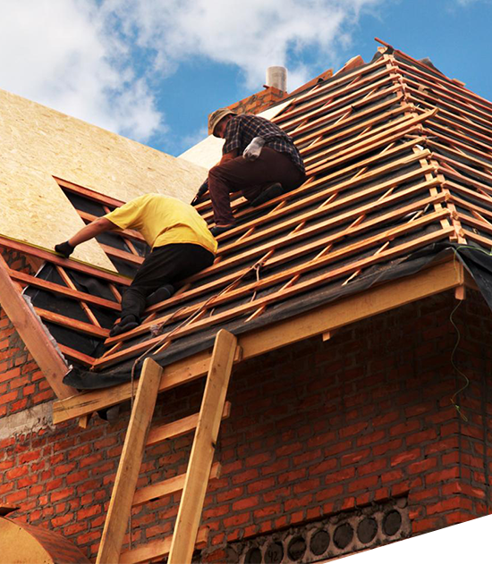 Two workers installing a wooden roof structure on a brick building with a ladder.