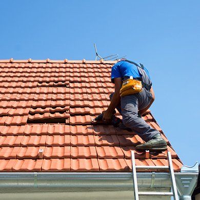 Person repairing terracotta tile roof on a sunny day.