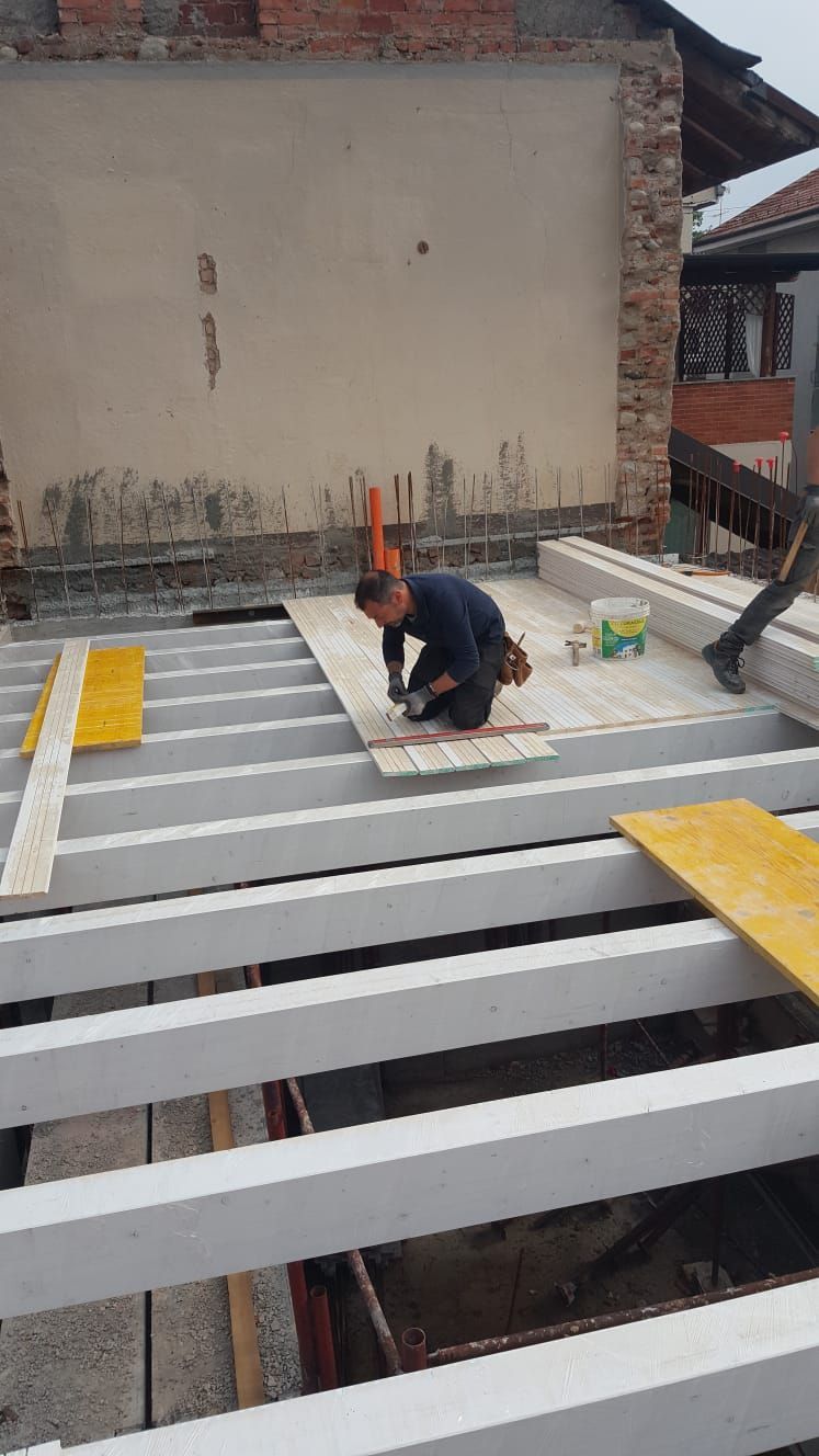 Operaio edile che installa assi di legno su travi di cemento.