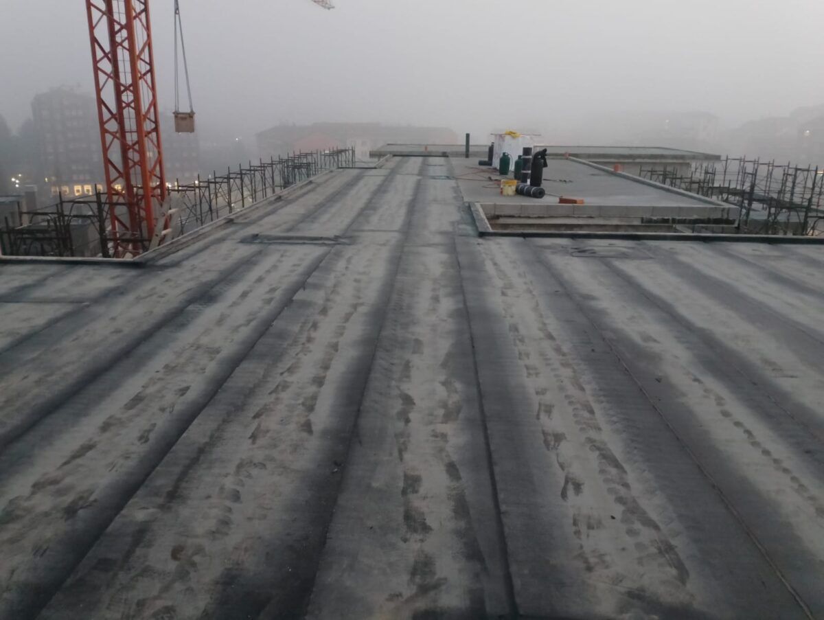 Cantiere con soletta di cemento, gru e sfondo nebbioso.