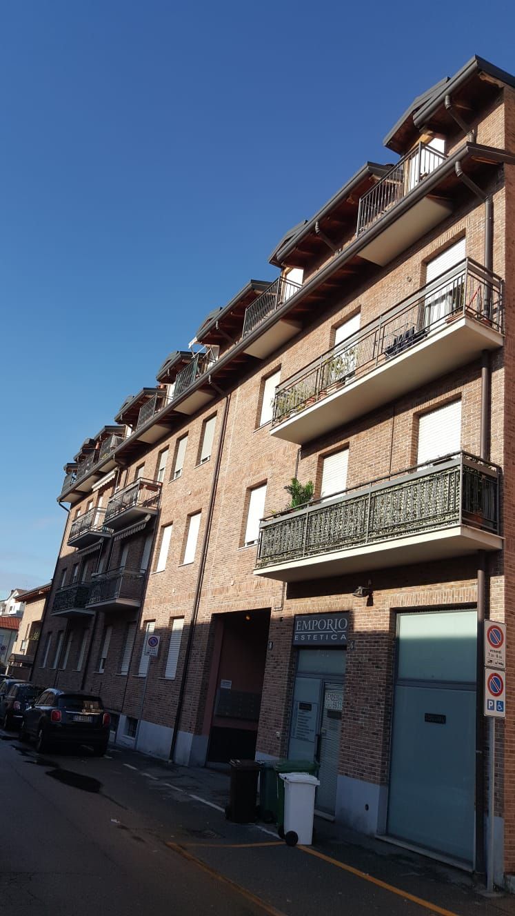 Edificio in mattoni con balconi, finestre e abbaini contro un cielo azzurro.