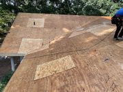 Workers installing plywood on a sloped roof under construction