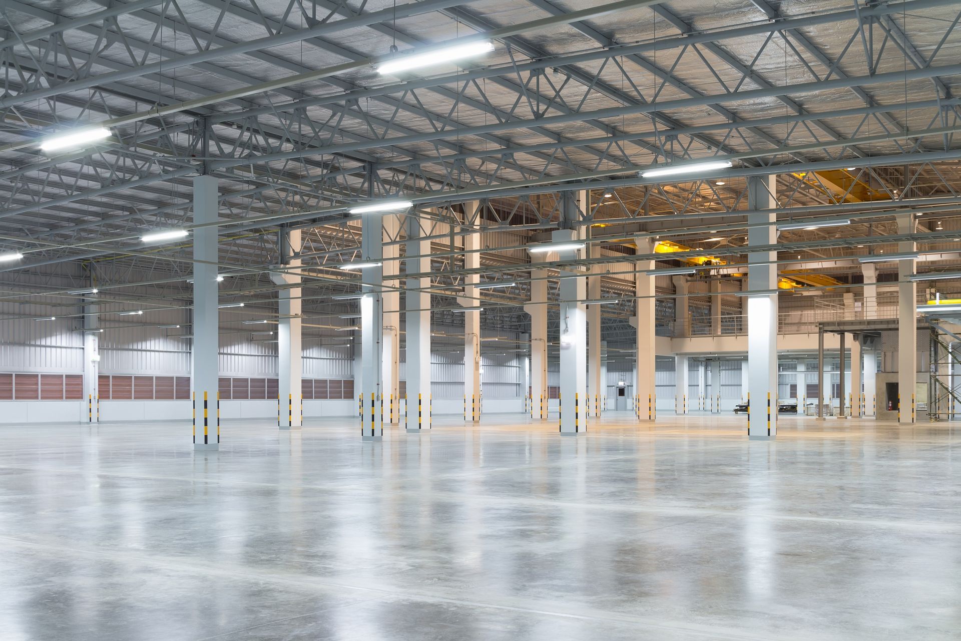 Empty industrial warehouse with high ceilings, metal beams, and polished concrete floor