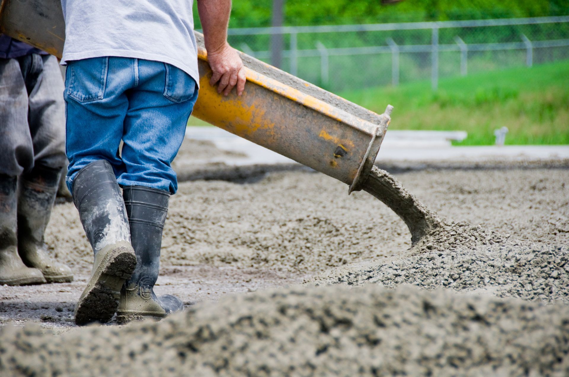 Worker pouring concrete from a chute onto a surface, construction site.