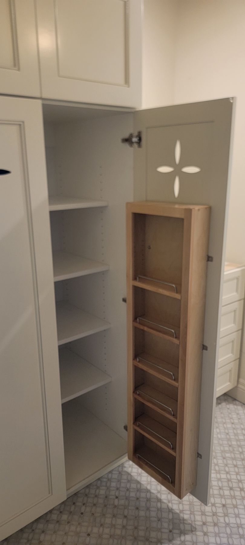 A spice rack is built into a cabinet in a bathroom.