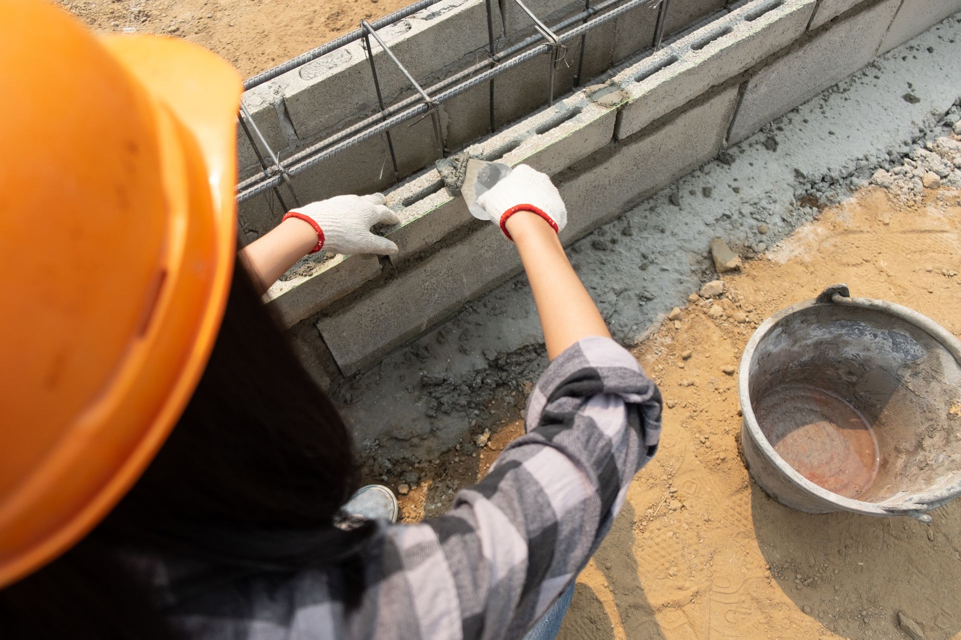Construction worker laying concrete blocks along a foundation trench