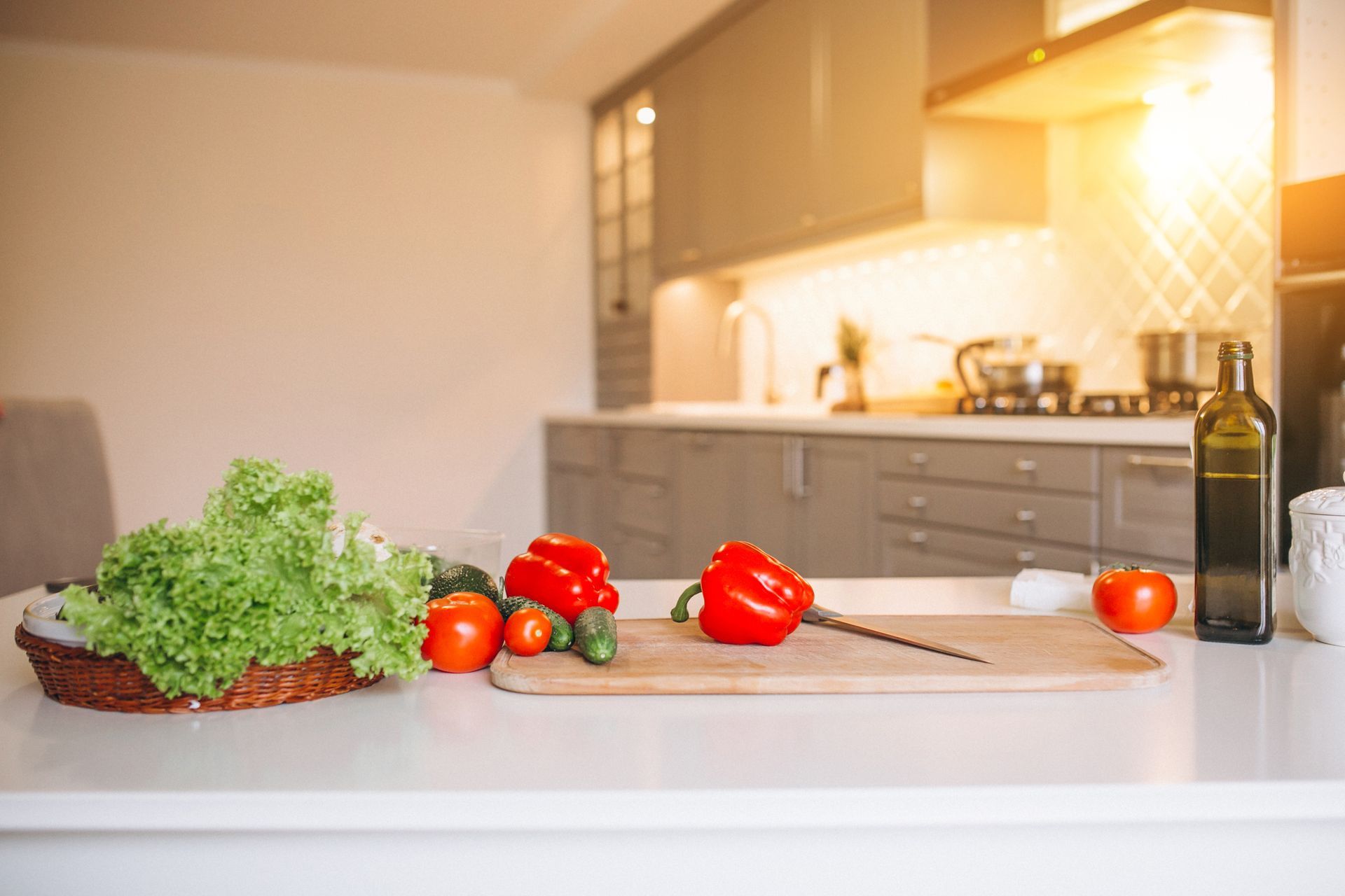 Fresh vegetables on a cutting board in a bright kitchen with a bottle of olive oil