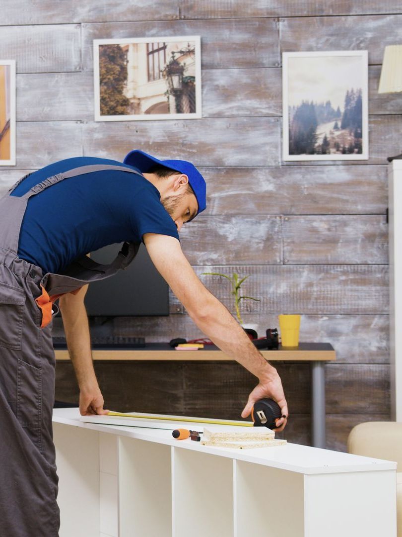 A man is measuring a shelf with a tape measure.