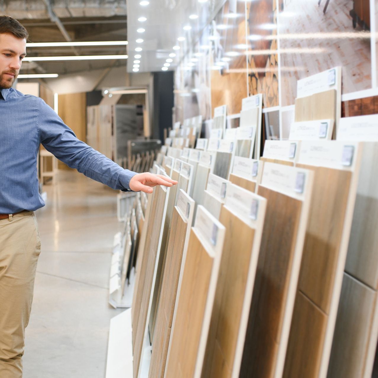 A man in a blue shirt is looking at tiles in a store