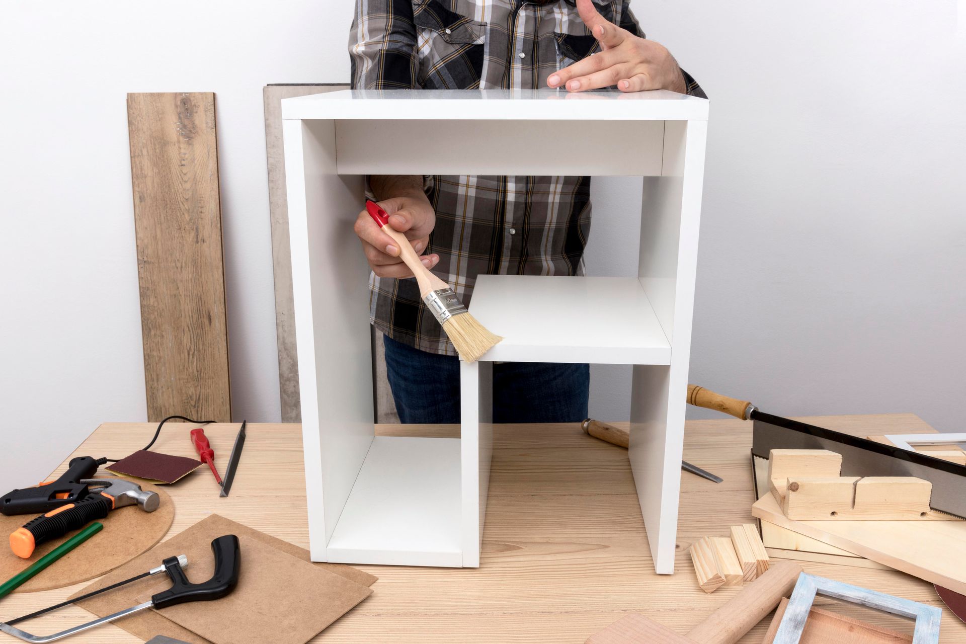 A man is painting a wooden shelf with a brush.