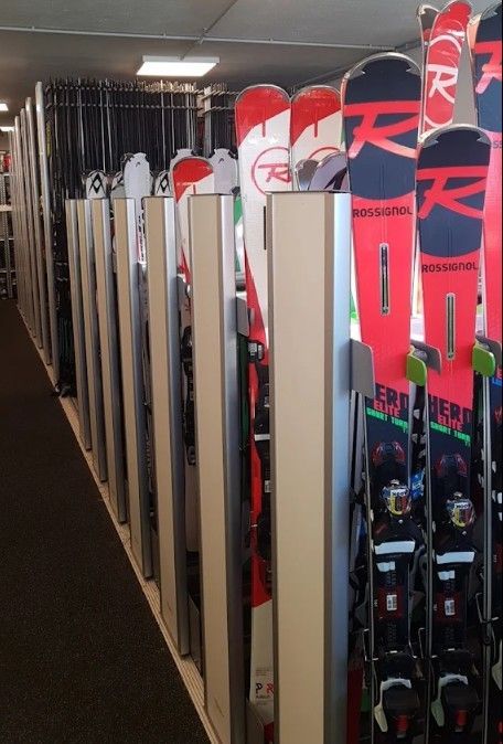 Una fila di sci rossi e bianchi riposti in verticale in uno stretto corridoio di un negozio di sci.