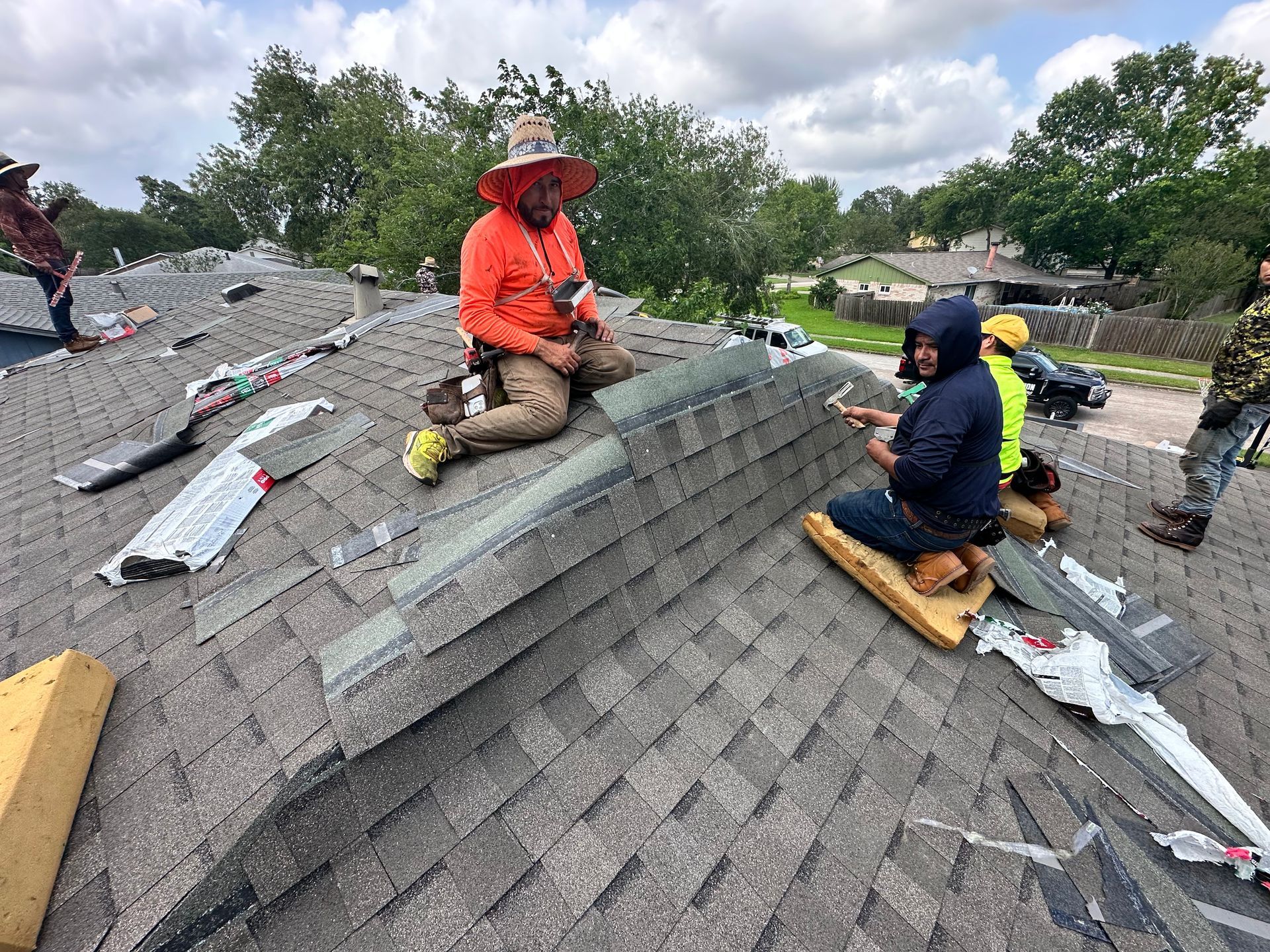 Roofers installing shingles on a residential roof, sunny day.