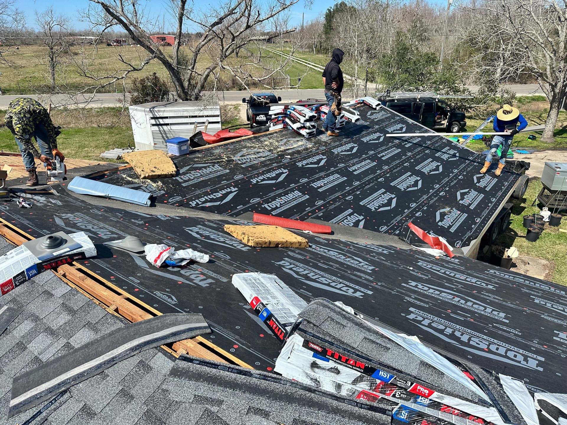 Construction workers installing roofing shingles on a building.