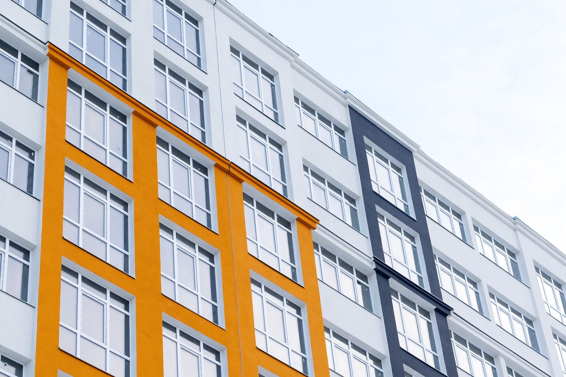 Modern apartment building facade with orange and gray sections and many white windows