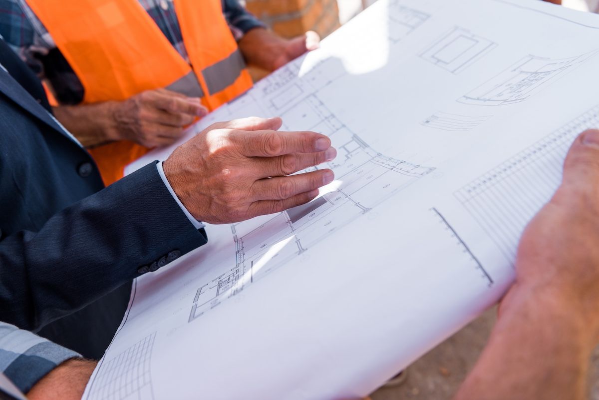 Hands reviewing architectural blueprints on a table in a meeting