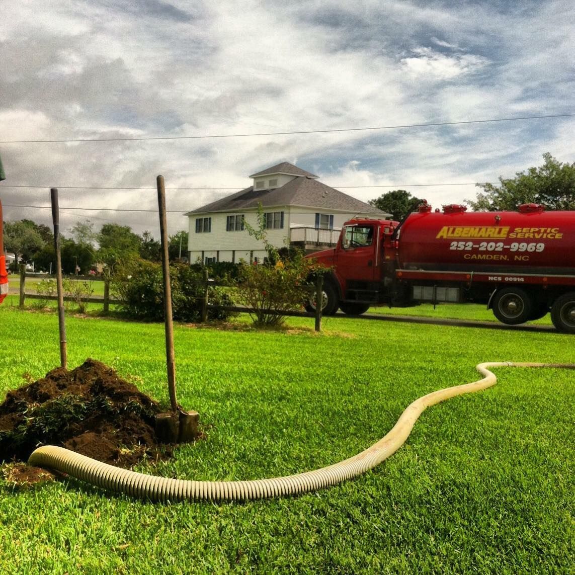A red vacuum truck with a green hose attached to it. A red vacuum truck with a green hose attached to it.