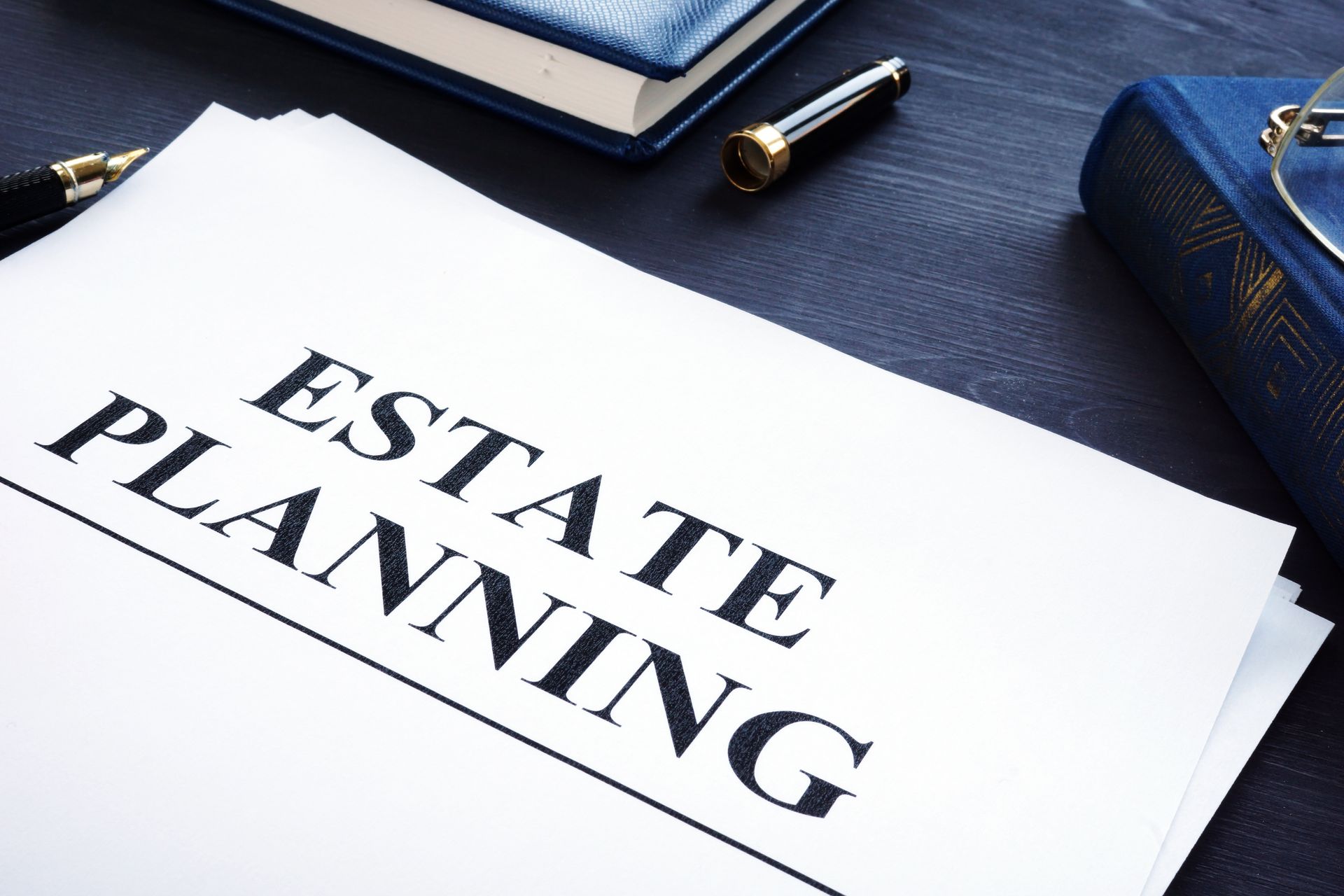 Document labeled “Estate Planning” on a desk with books and a pen.