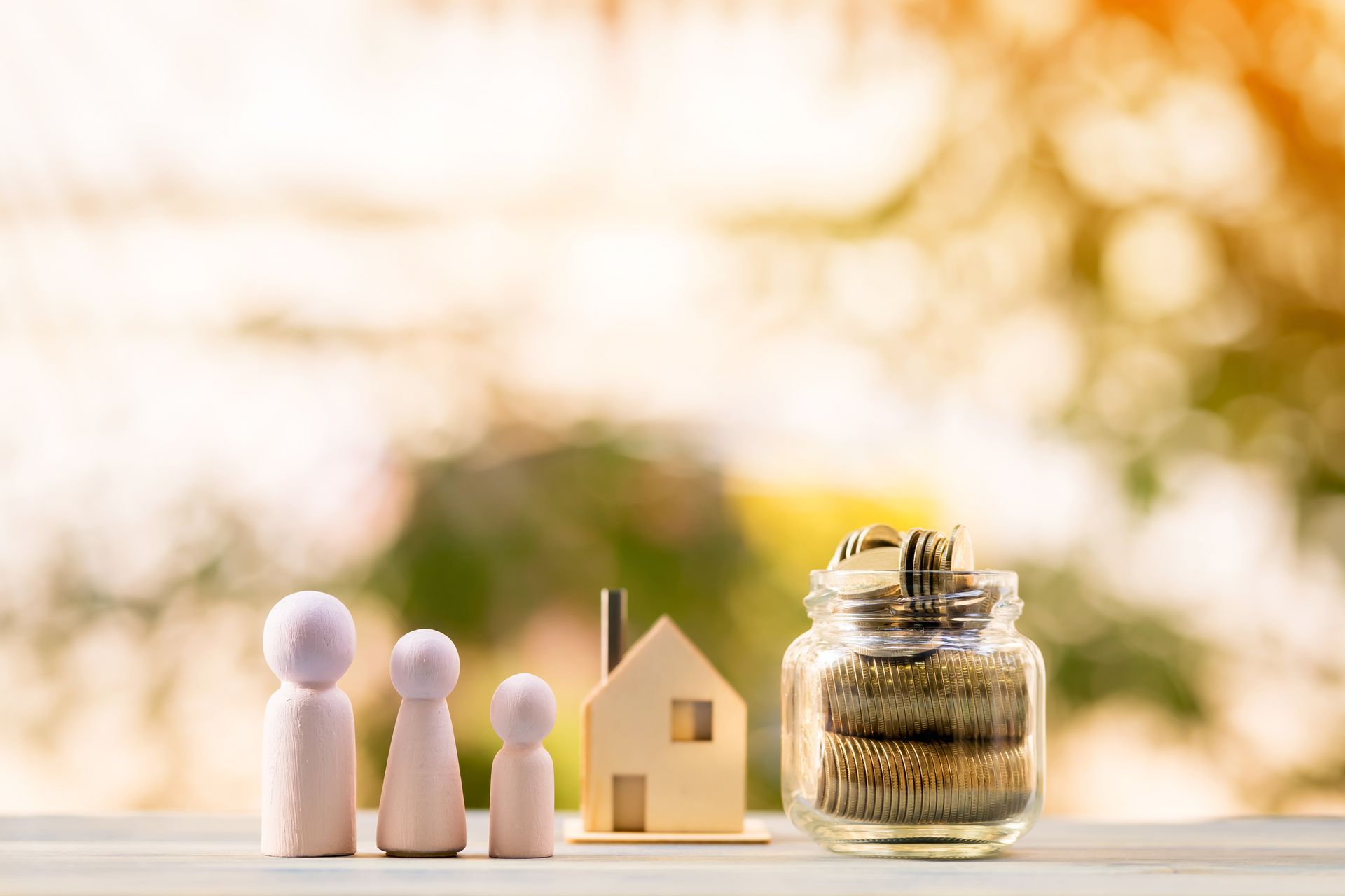 A model house, wooden family figures, and a bottle of gold coins representing real estate investment