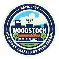 City of Woodstock, Georgia seal. Features text, buildings, blue/green/orange color scheme. “Our story crafted by your dreams.”