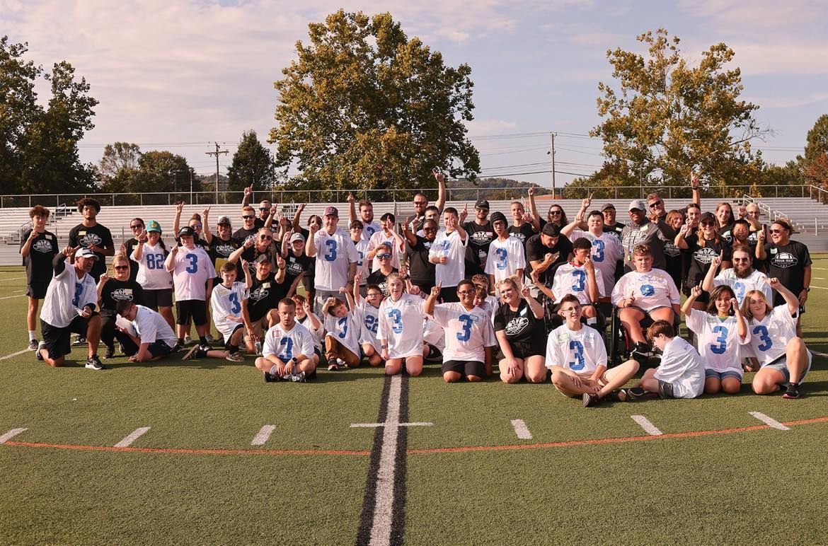 Large group on a football field wearing white jerseys with 