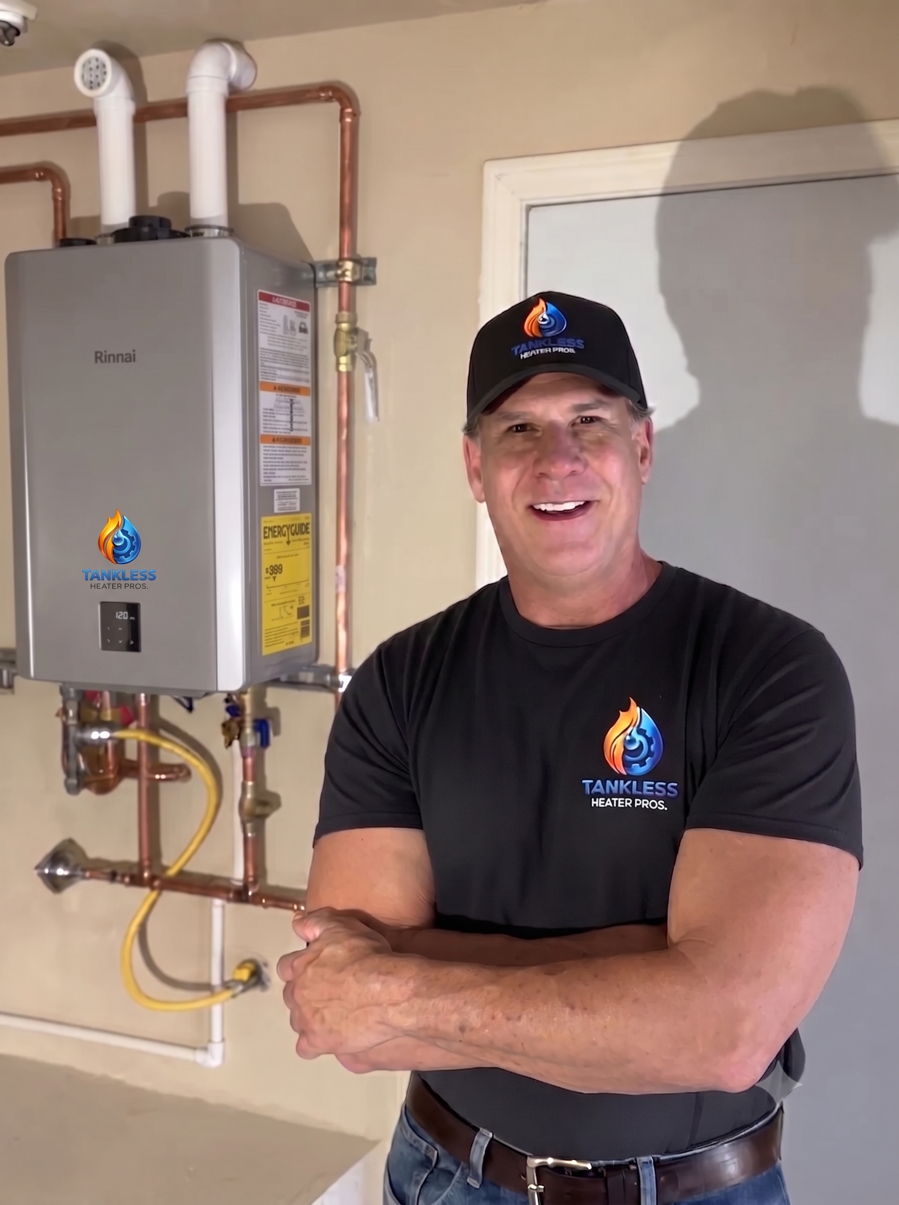 Plumber standing beside a wall-mounted water heater and copper pipes, arms crossed, in a utility room.