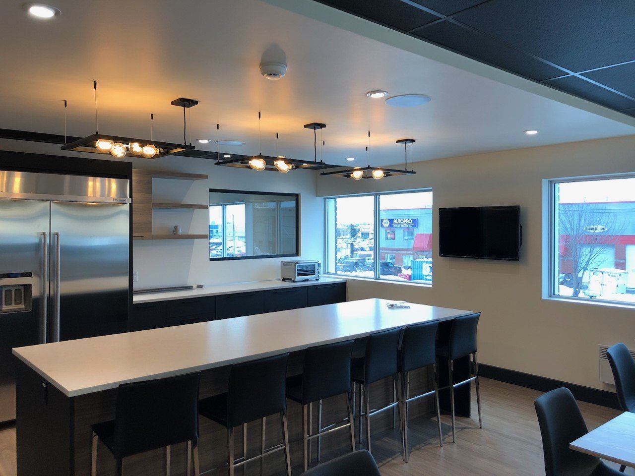 Cuisine moderne avec îlot central, appareils électroménagers en acier inoxydable et fenêtres donnant sur une rue urbaine.