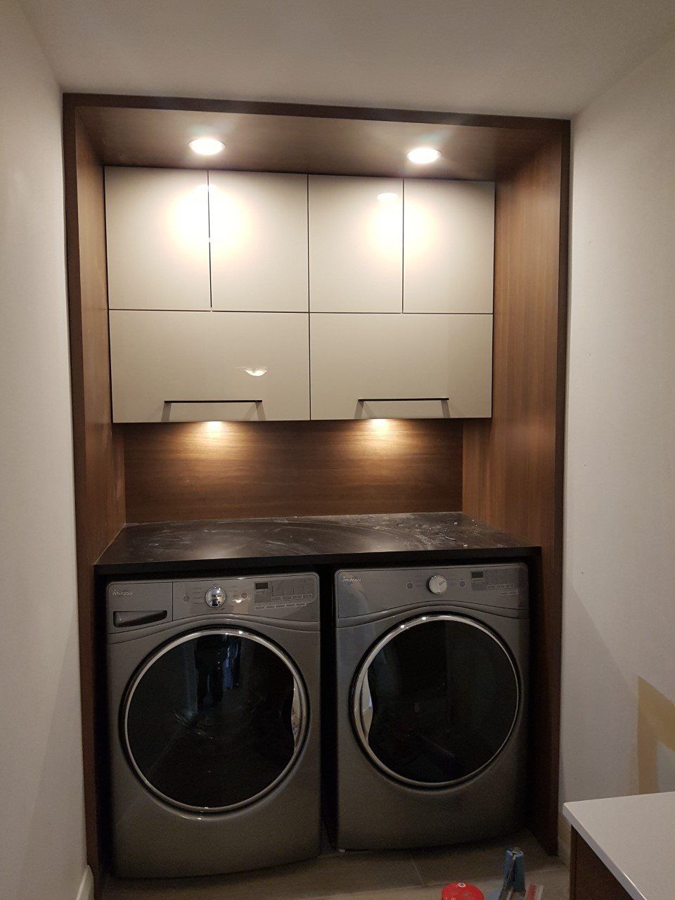 Buanderie avec lave-linge, sèche-linge, placards et plan de travail.