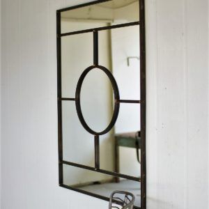 Black metal wall mirror with oval center, reflected in a white interior wall