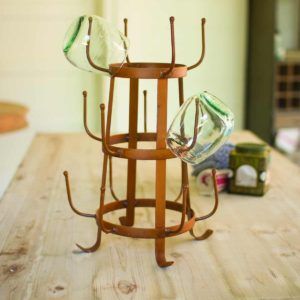 Wooden wine rack on a table with two clear glasses hanging on the top and side.