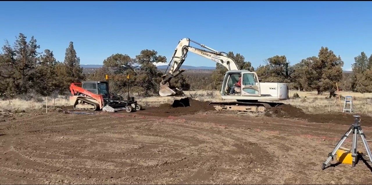 Track loader clears and levels land during early residential site prep near homes.